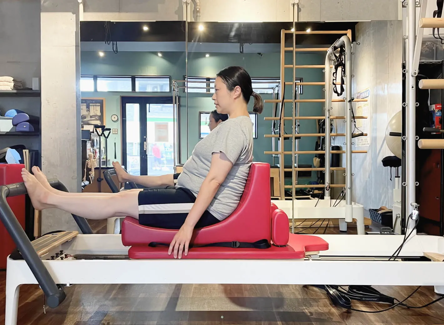 ピラティスタジオBB 武蔵小杉でリフォーマーの上にC-shaperを使用してマタニティピラティスを実践している妊娠後期のクライアントの写真