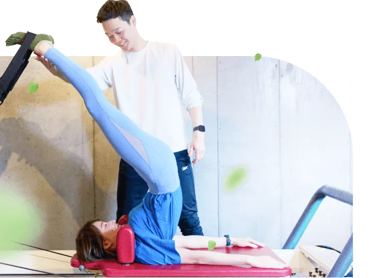 ピラティスを指導する男性とピラティスをする女性の写真