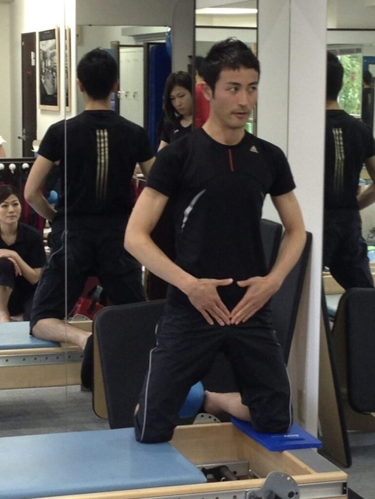 ピラティススタジオBB 南青山の出井和也さんが、クリニカルリフォーマーを活用し、ヒップアダクションの解説をしている写真