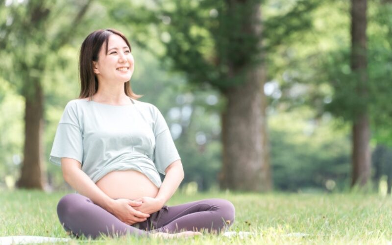 芝生の上で座っている妊婦の画像
