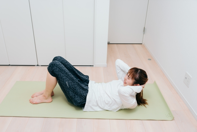 ピラティスの基本ポーズのひとつであるチェストリフトを自宅で実践する女性