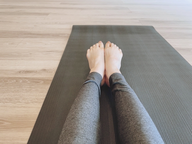 ピラティスの基本姿勢をとるための準備をしている女性の足元