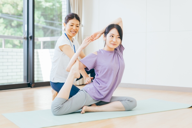 ピラティスの個人指導で、インストラクターがポーズを取りボディメイクを目指す女性をサポート