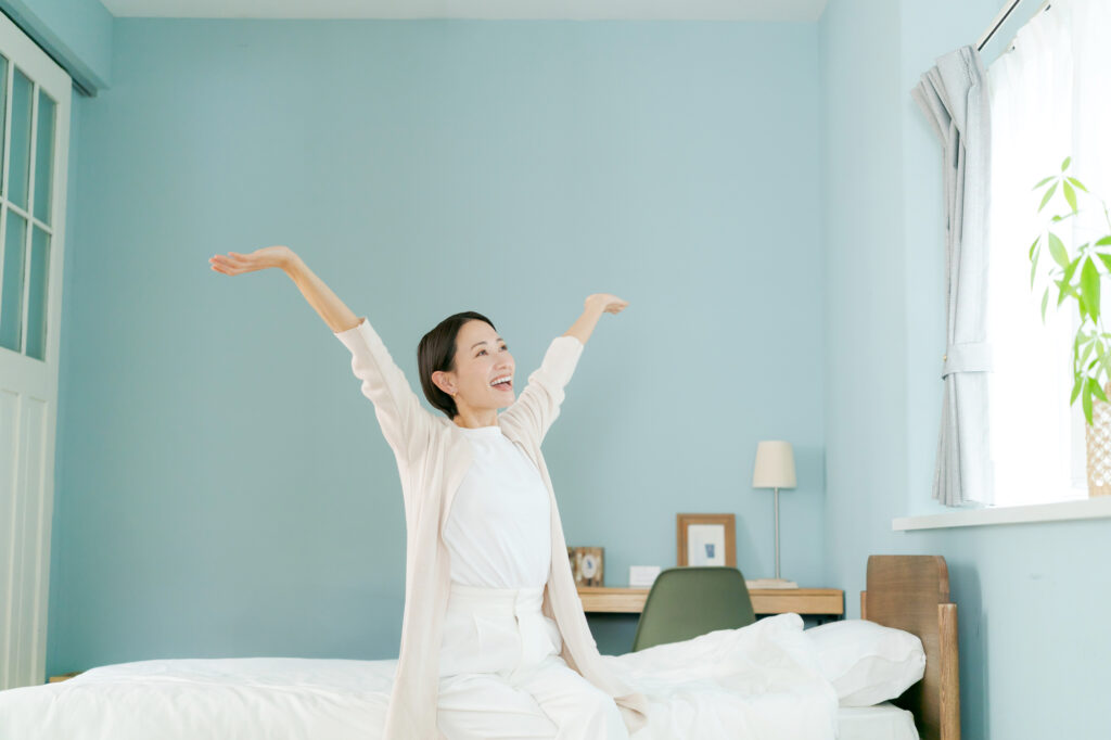 朝に気持ちよくノビをしている女性のイメージ画像