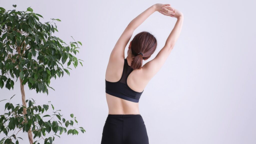 錦糸町でピラティスを始めるメリットである、美しい姿勢作りや柔軟性向上に効果的なストレッチを行う女性の背面。
