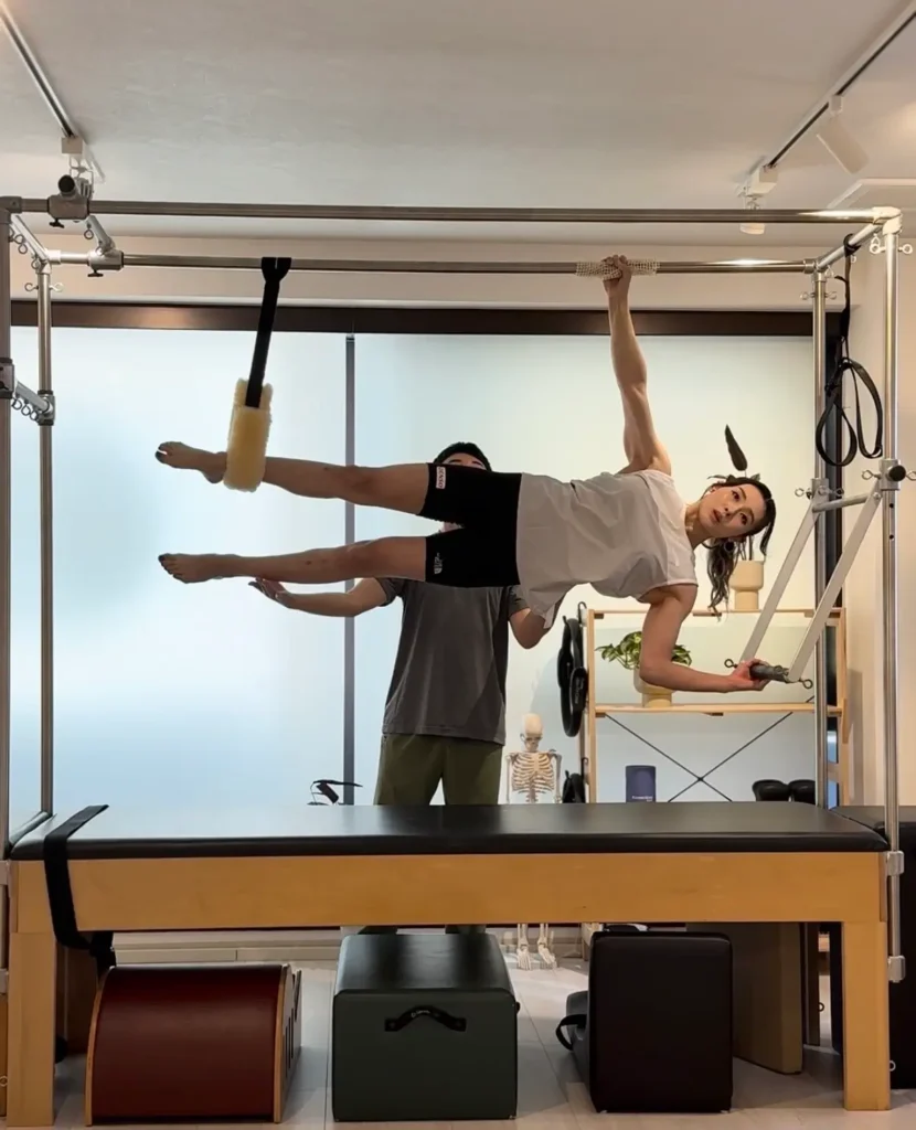スポーツクライミングの伊藤ふたば選手がトラピーズテーブルでピラティスセッションを受けている画像